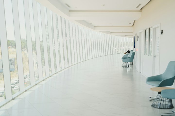 An empty, bright hallway with a row of chairs along the wall