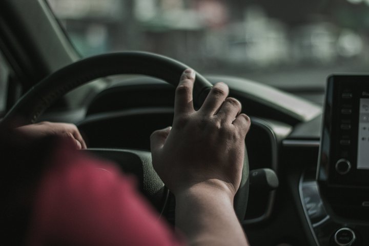 A driver's hand resting on a steering wheel