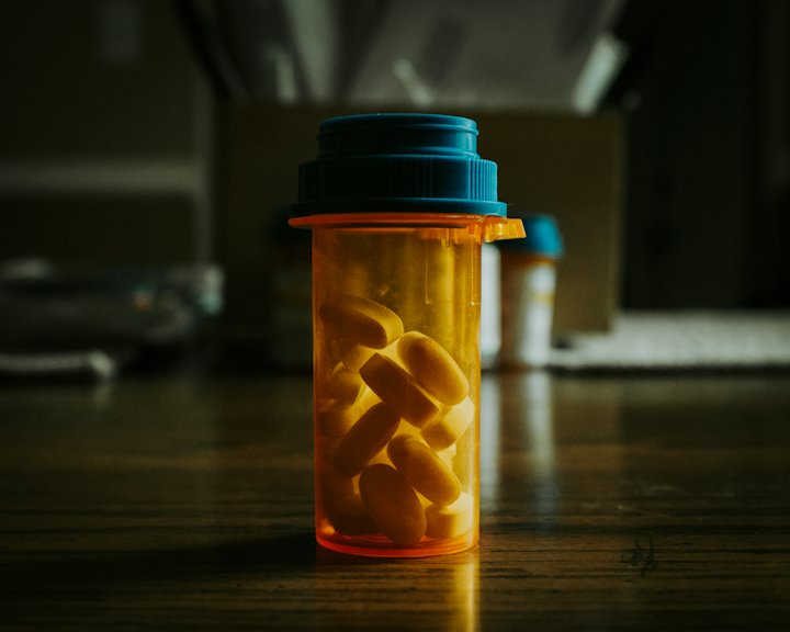 A prescription bottle filled with capsules standing on a wooden table